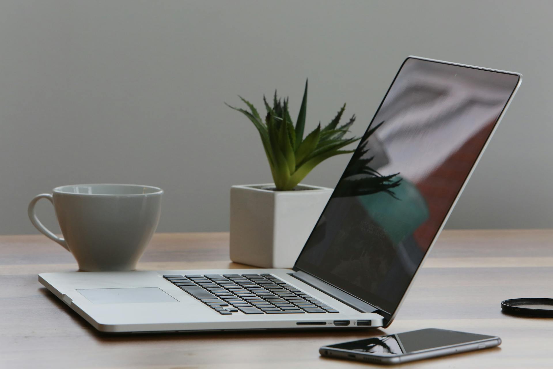 Silver Laptop and White Cup on desk next to smart phone