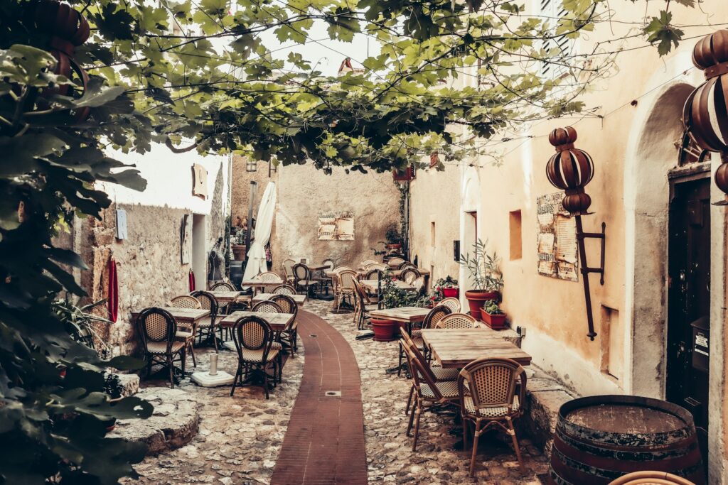 a courtyard with tables and chairs under a tree in the Eze village of france