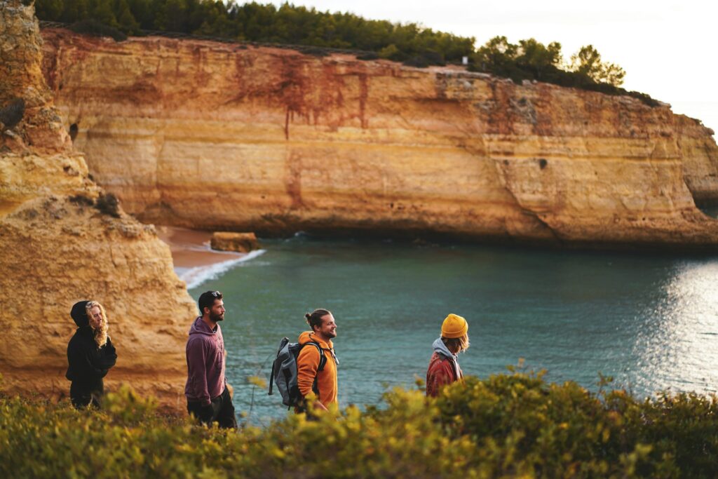 a group of people hiking on top of a cliff next to the ocean