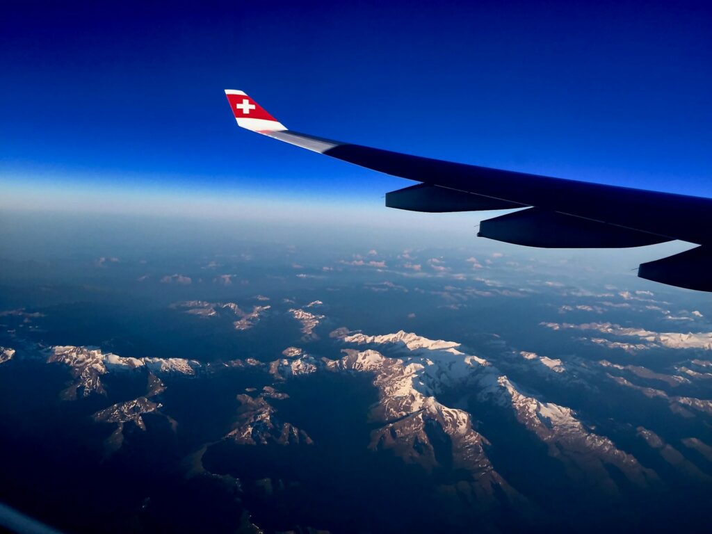 a view of snowy mountain peak from the window of an airplane with a view of the wing