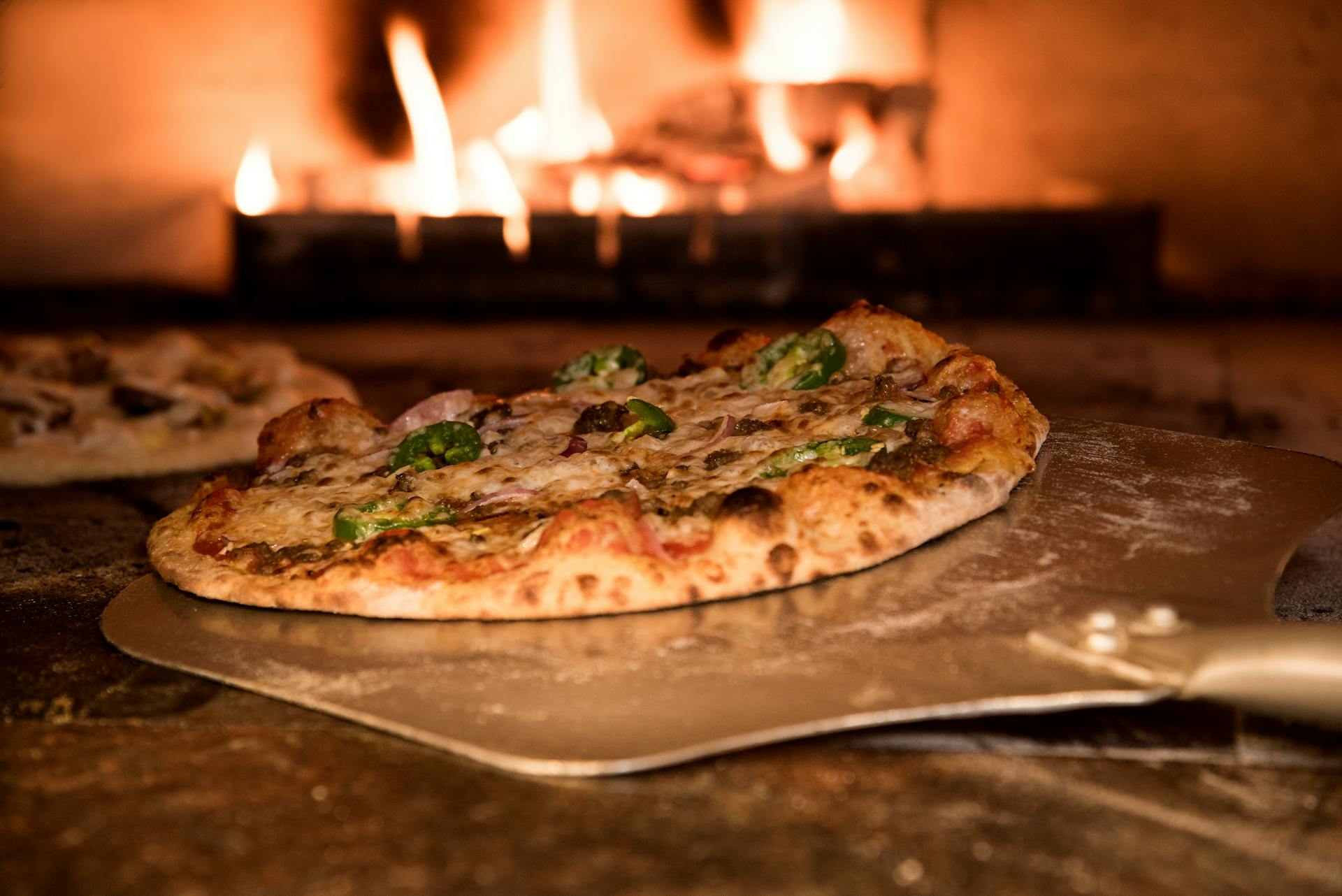 handmade pizza being pulled out of a pizza oven