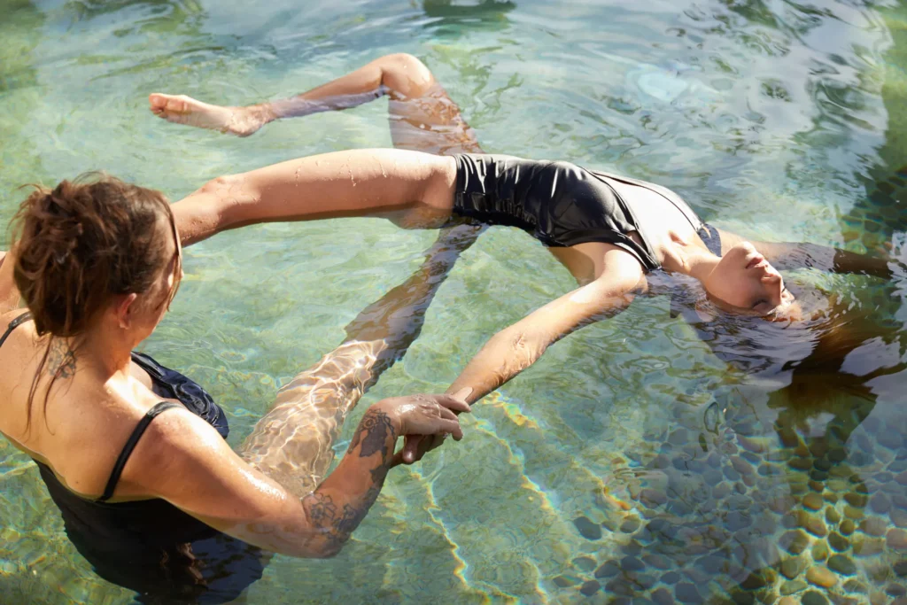 two woman in a pool of water stretching and relaxing