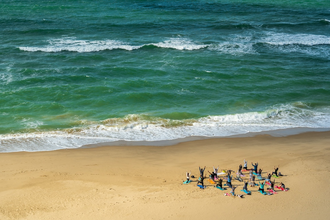 a group of people doing yoga on the beach