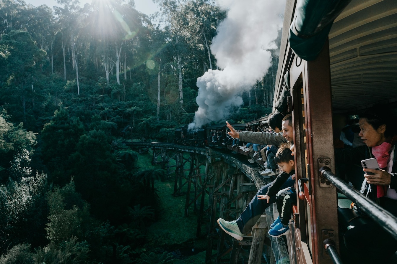 a group of people riding a train over a ravine with open sides