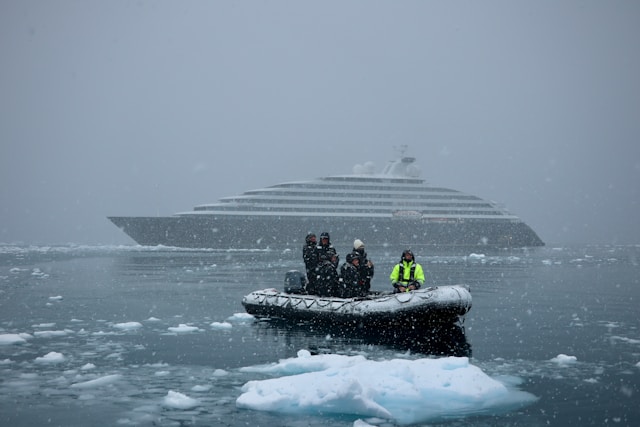 a small raft in the water during an antarctic blizzard with the ship in the background and ice floating around them