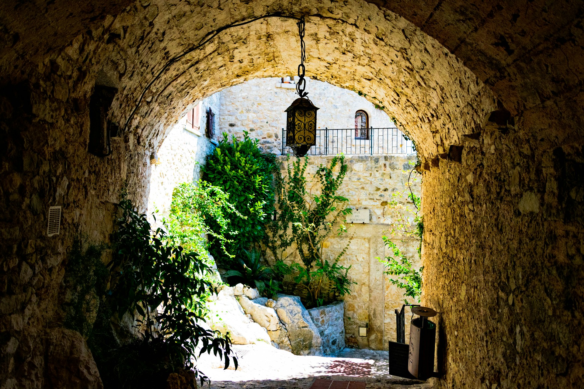 a stone tunnel with a light over it in eze france