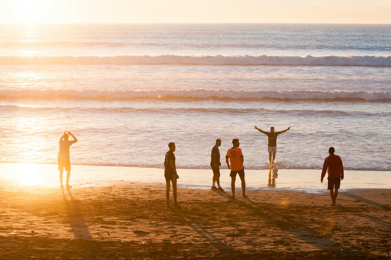 family playing soccer on the beach at sunset