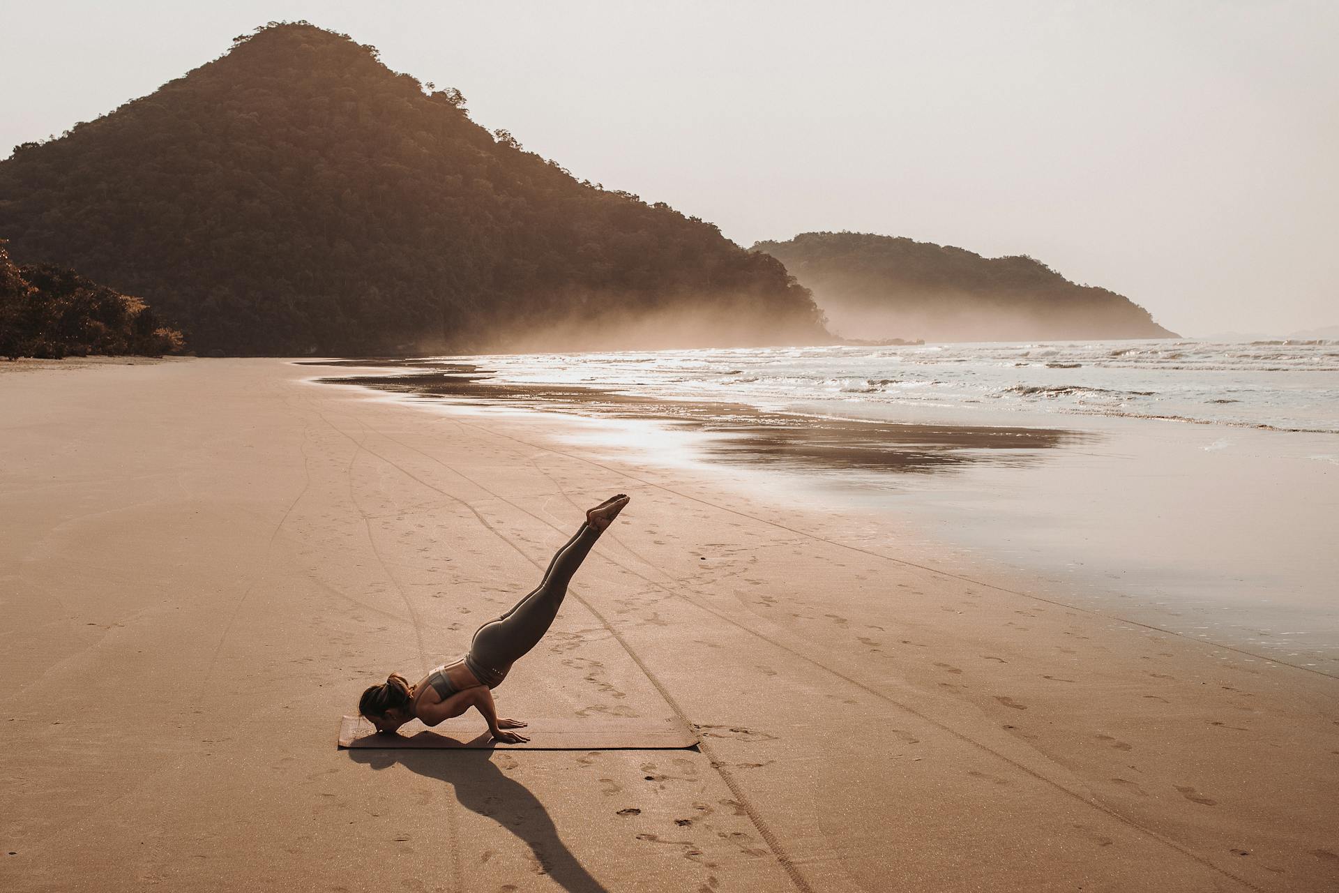 far away shot of woman doing yoga on the beach