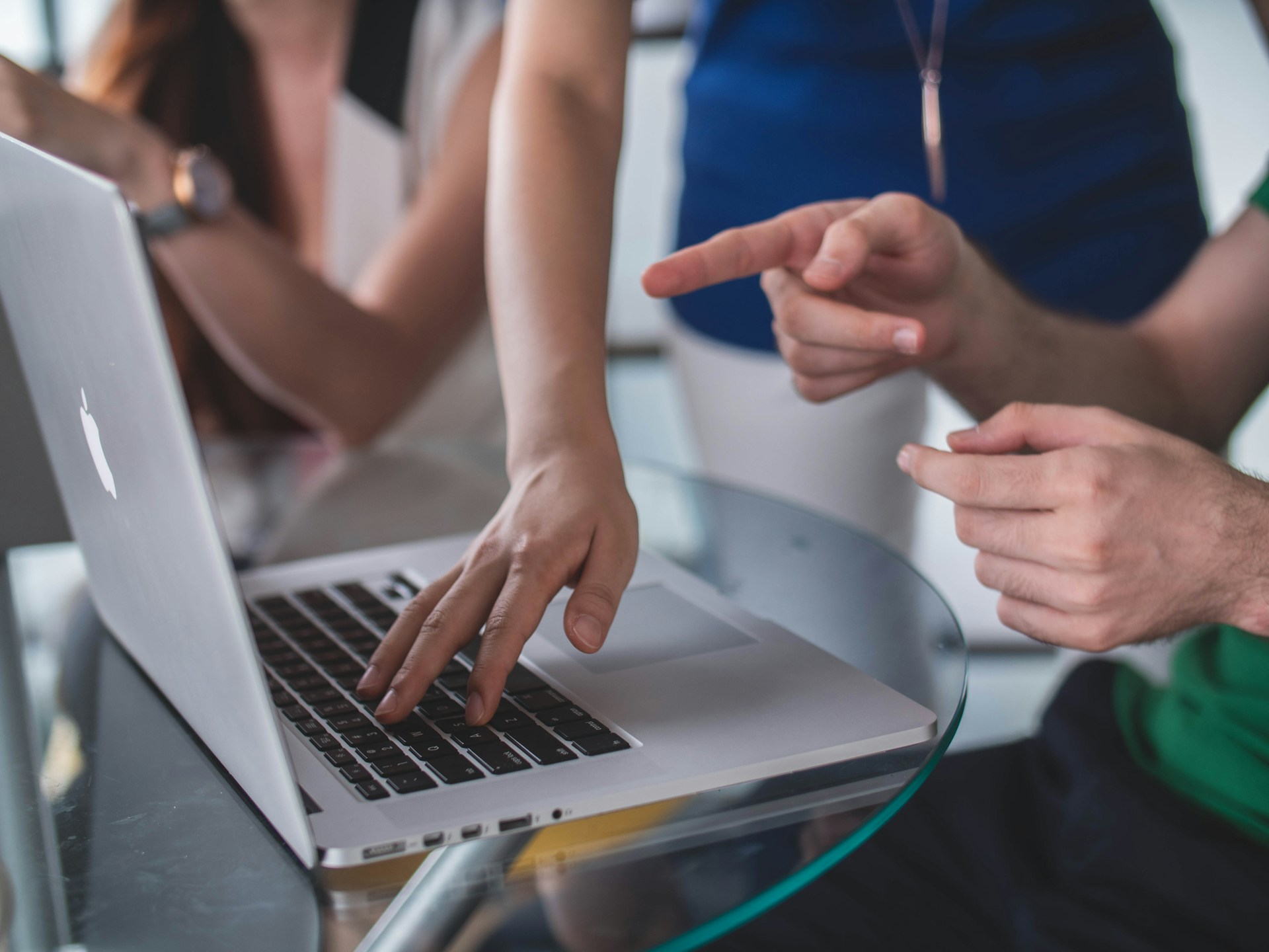 people looking at and point at something on the screen of a macbook