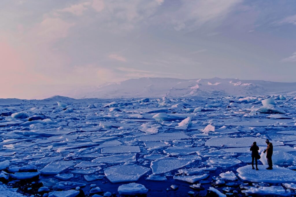 people standing on cracked ice on the ocean under an icy sky