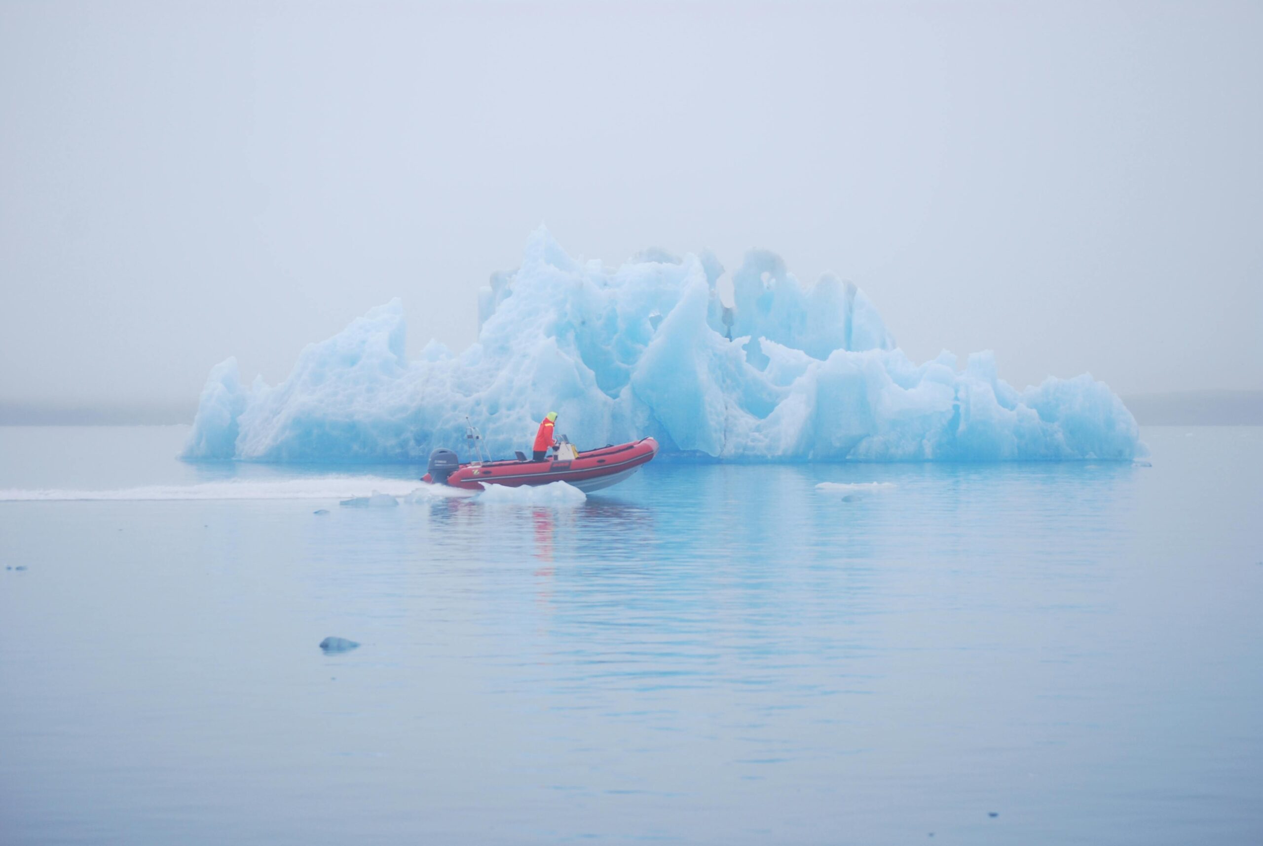 person on an excursion raft sailing past an iceburg