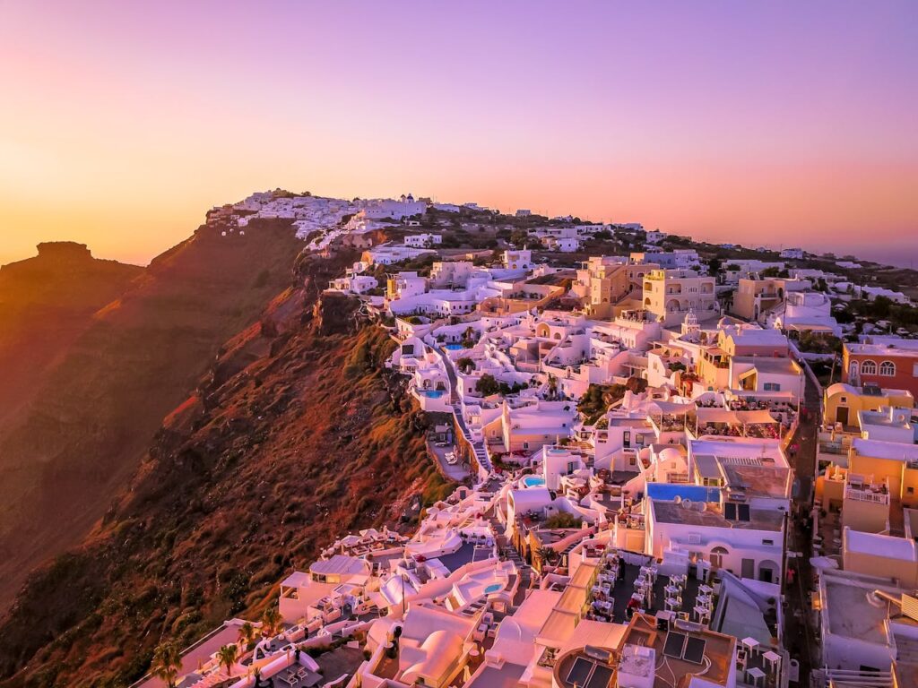 white buildings on the edge of a cliff at sunrise