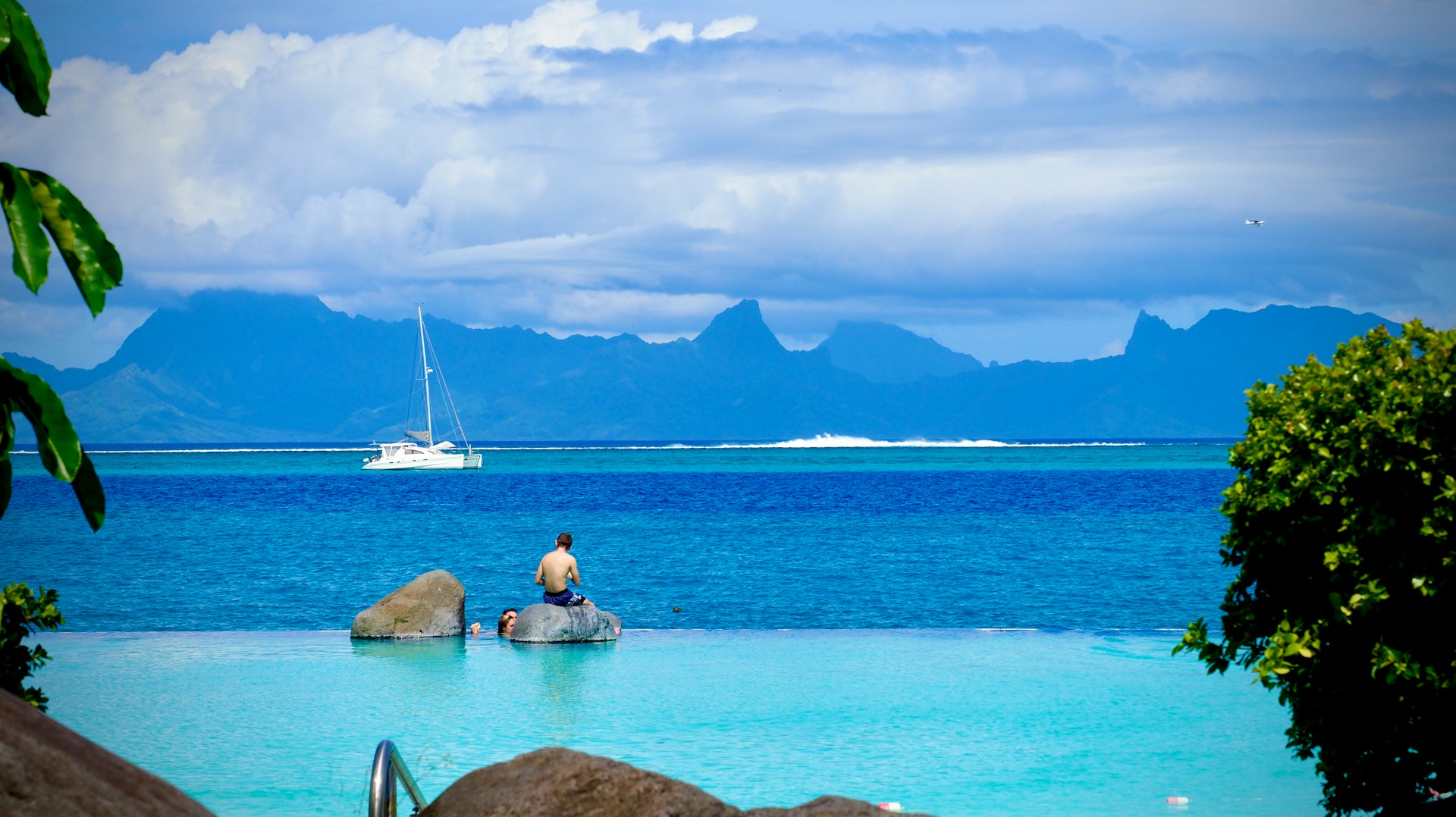 white sail on the ocean as seen from an infinity pool in tahiti