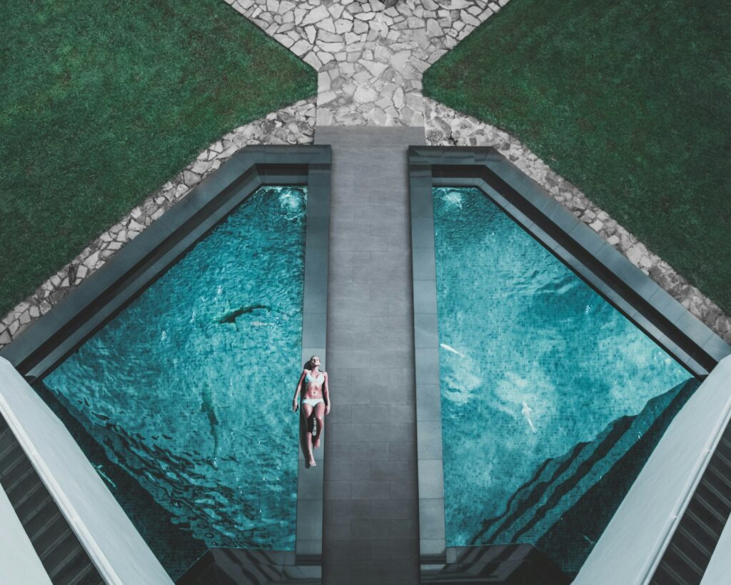 woman lying in luxury swimming pool surrounded by grass