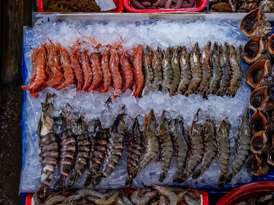 whole prawns sitting on ice at a fish market