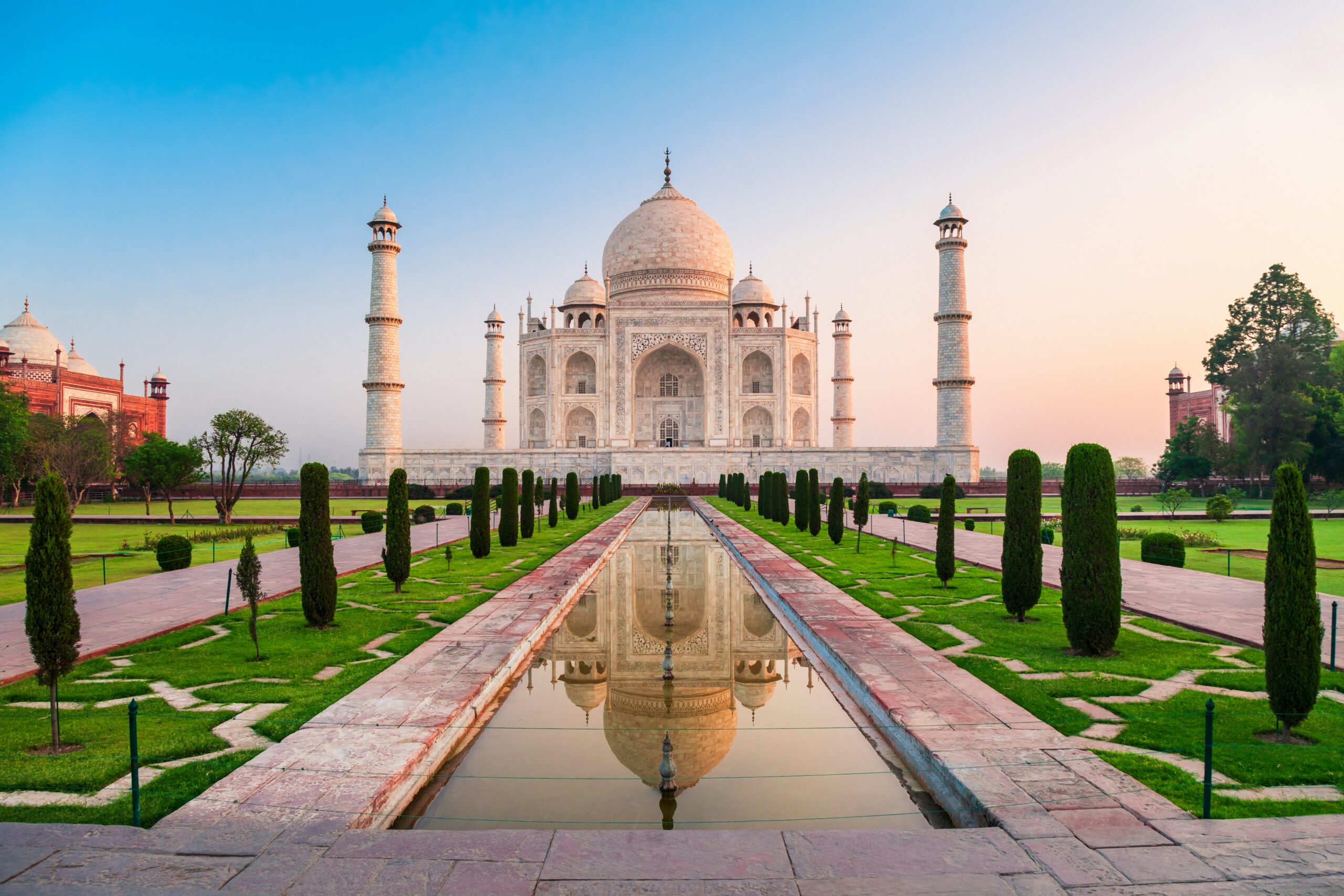The Taj Mahal at sunrise with soft light on the marble and a full reflecting pool